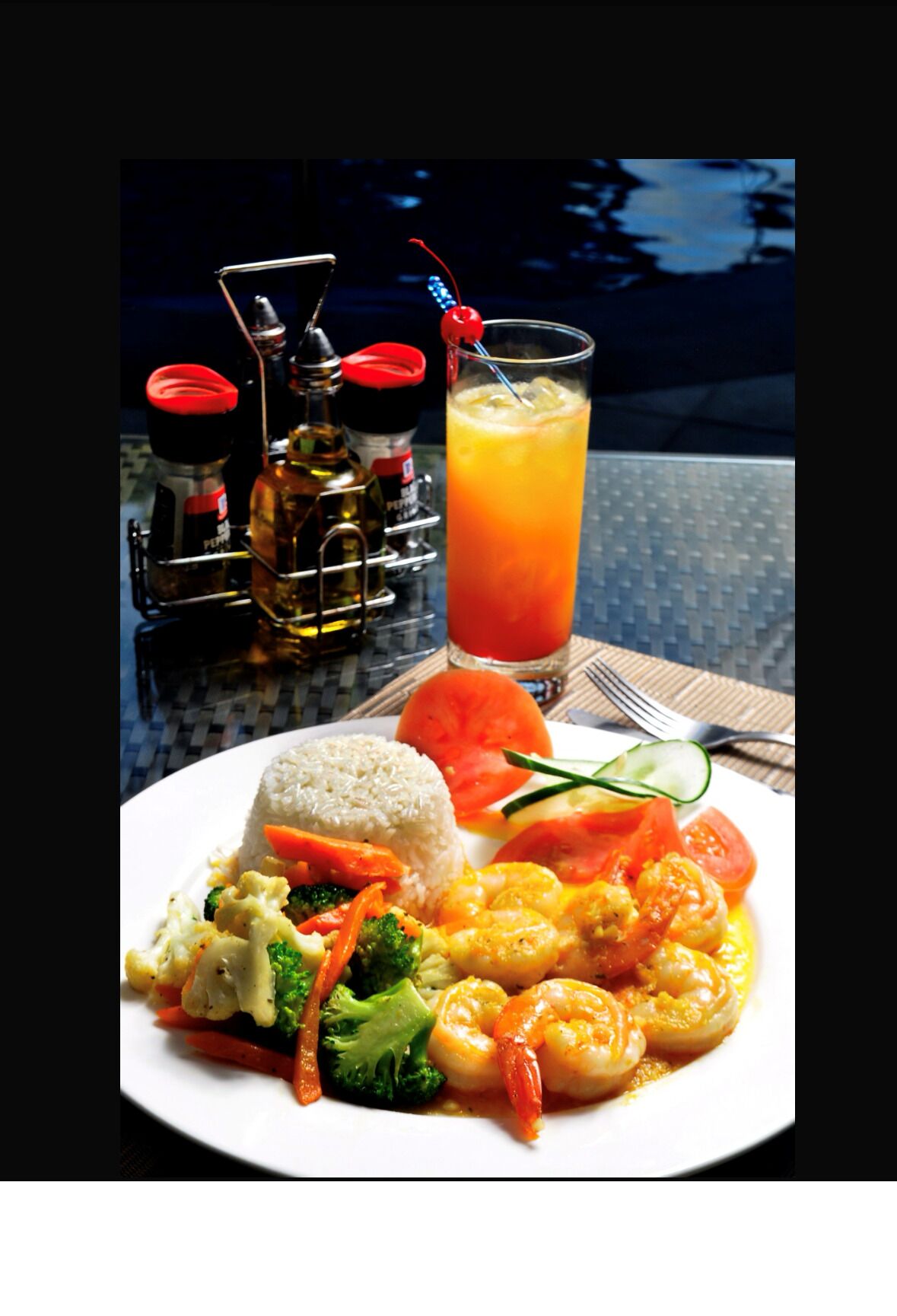 A plate of shrimp, rice, and vegetables with a glass of orange juice.