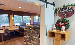 Interior de restaurante con pared de piedra, mesas de madera y decoración festiva.