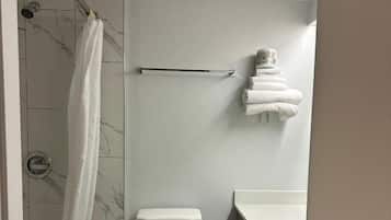 A modern bathroom with a toilet, shower, and sink.