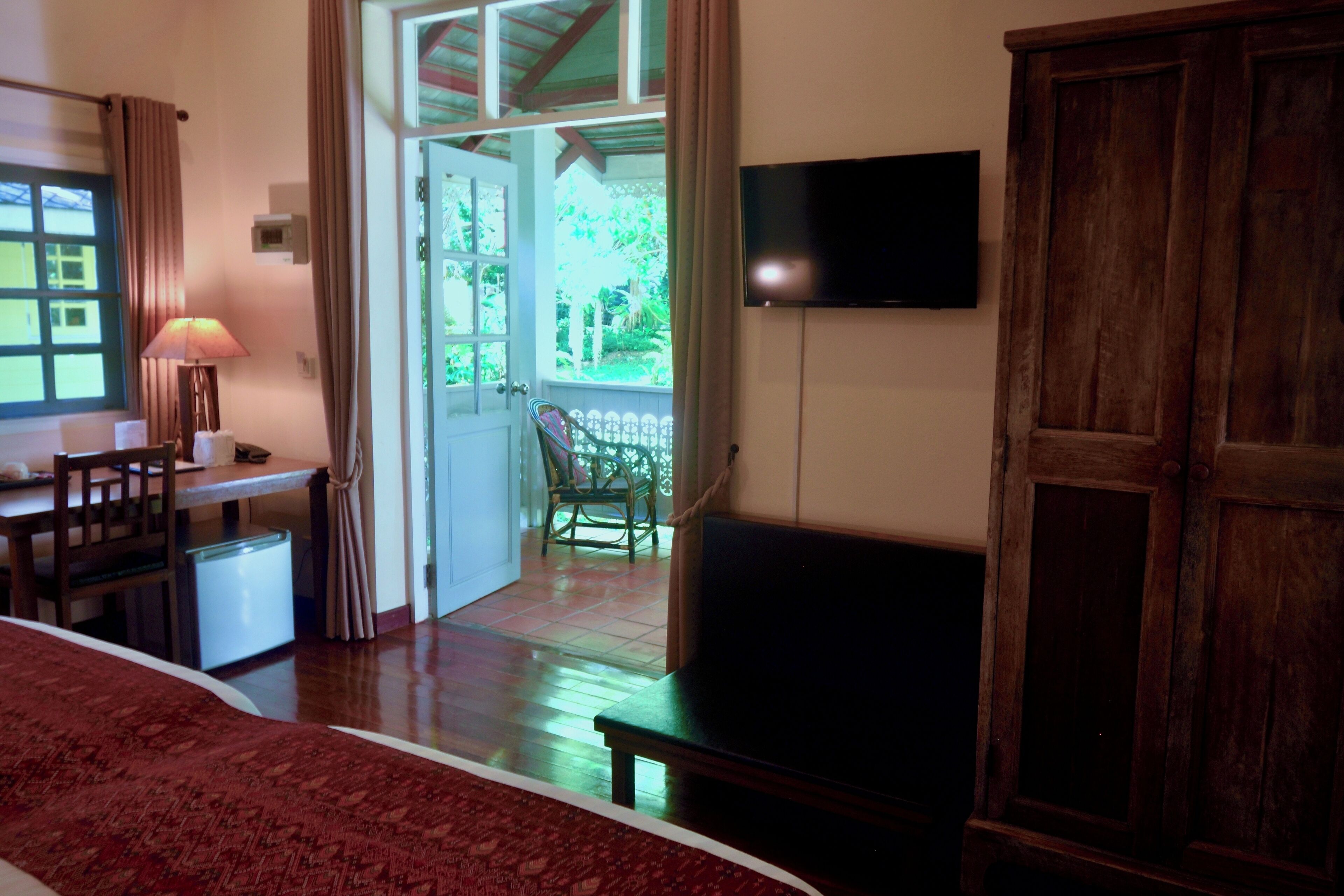 A room with a bed, a desk, a chair, a TV, and a wooden wardrobe.