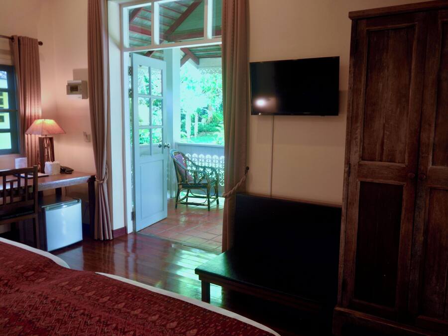 A room with a bed, a desk, a chair, a TV, and a wooden wardrobe.