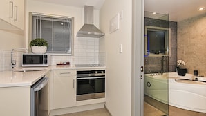 A modern kitchen with a dishwasher, microwave, oven, and a potted plant. - Newlands Court Motel (Wellington)