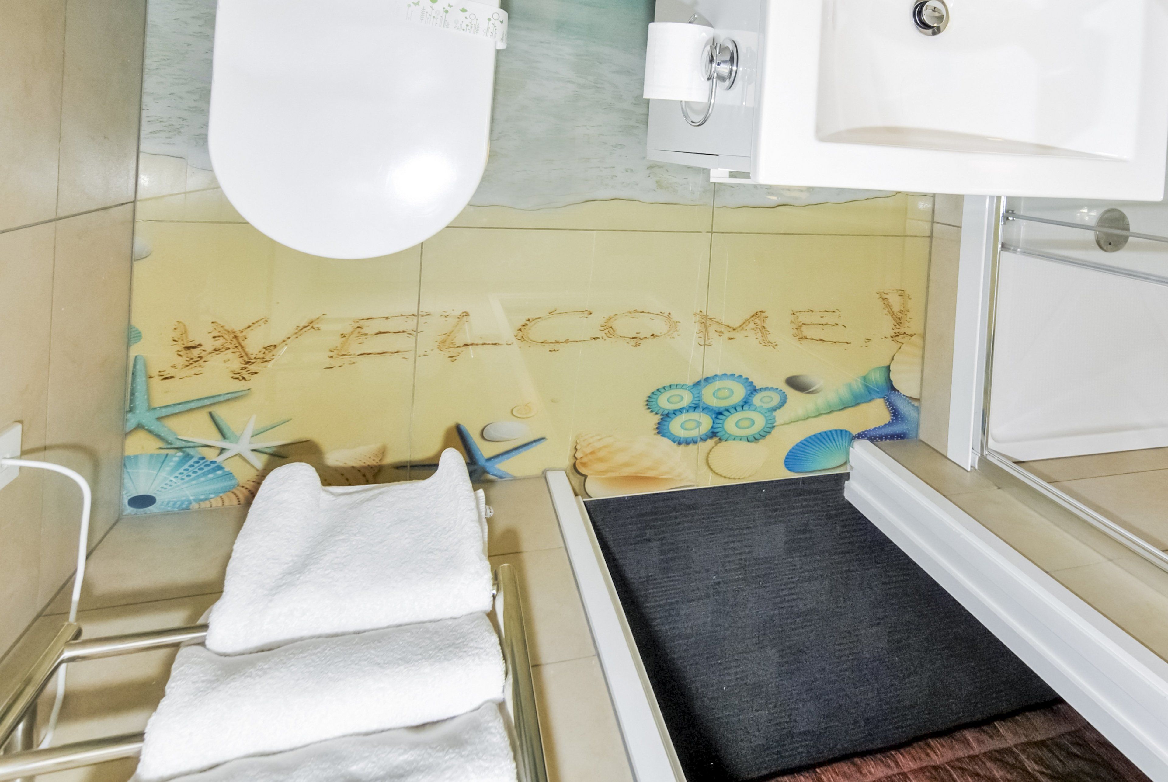 Une salle de bain avec une pancarte « BIENVENUE », une baignoire, un porte-serviettes et un espace douche.