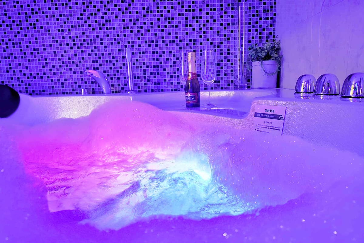 A bathtub with a water feature, a bottle of champagne, and a sign with text.