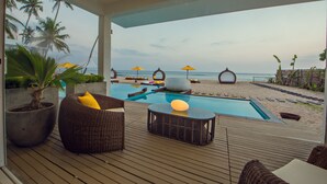 Un espace aménagé au bord de la piscine, avec des chaises longues, une petite table et des parasols.