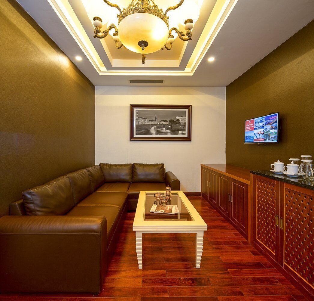 A modern living room with a brown leather sofa, a glass-top coffee table, a framed black and white photo on the wall, and a television on the right.