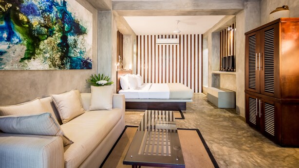 Una habitación de hotel moderna con una cama grande, un sofá, una mesa de centro y un mueble para la televisión.