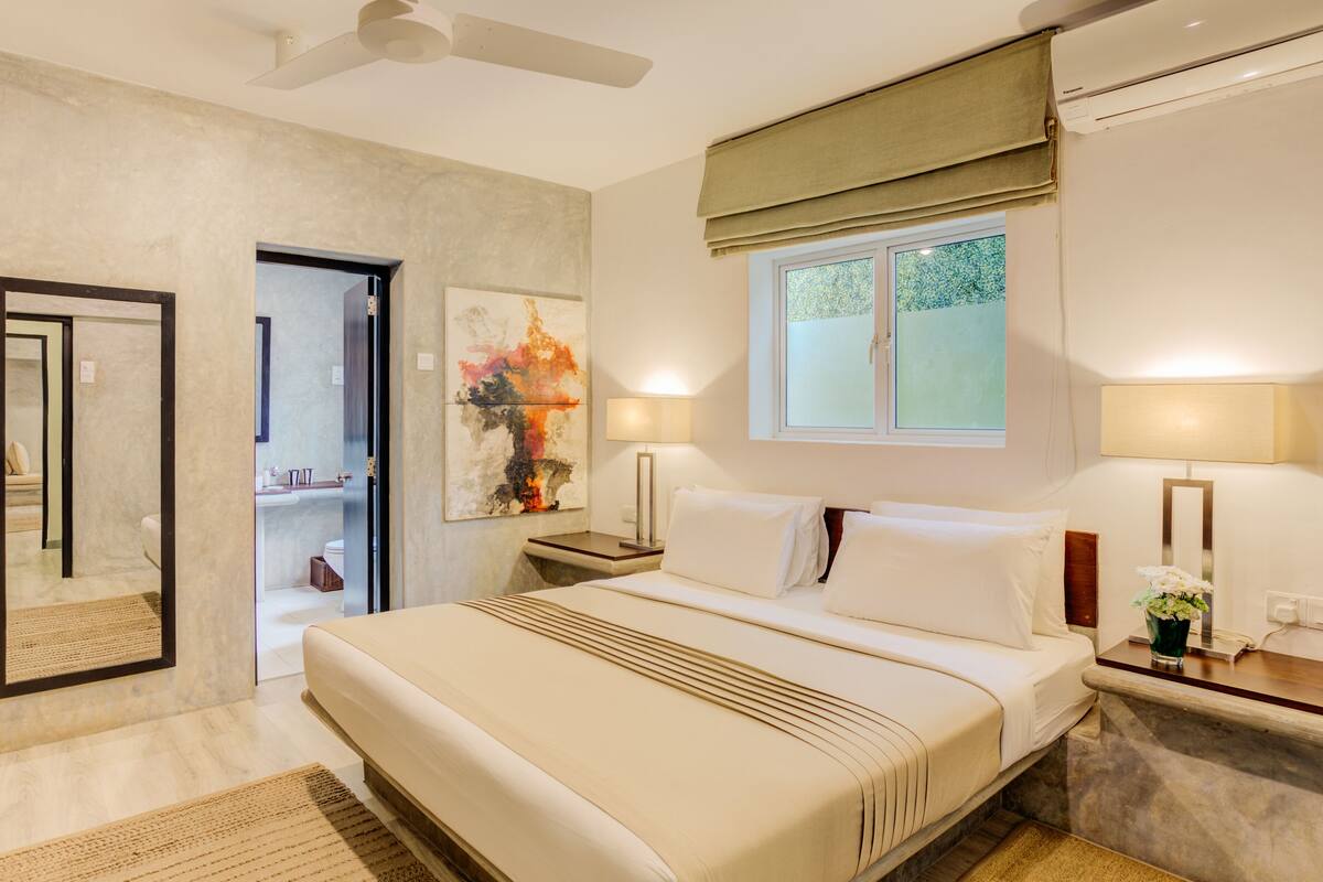 A modern bedroom with a large bed, bedside lamps, a window with a view, and a ceiling fan.