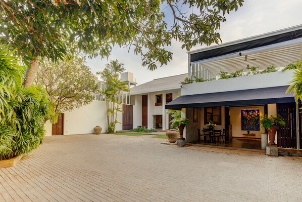 A courtyard with a paved walkway, a building with a covered outdoor seating area, and various potted plants. - Nyne Hotels Lake Lodge - Colombo (Colombo)