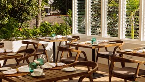 Un restaurante con mesas y sillas de madera, dispuesto para comer.