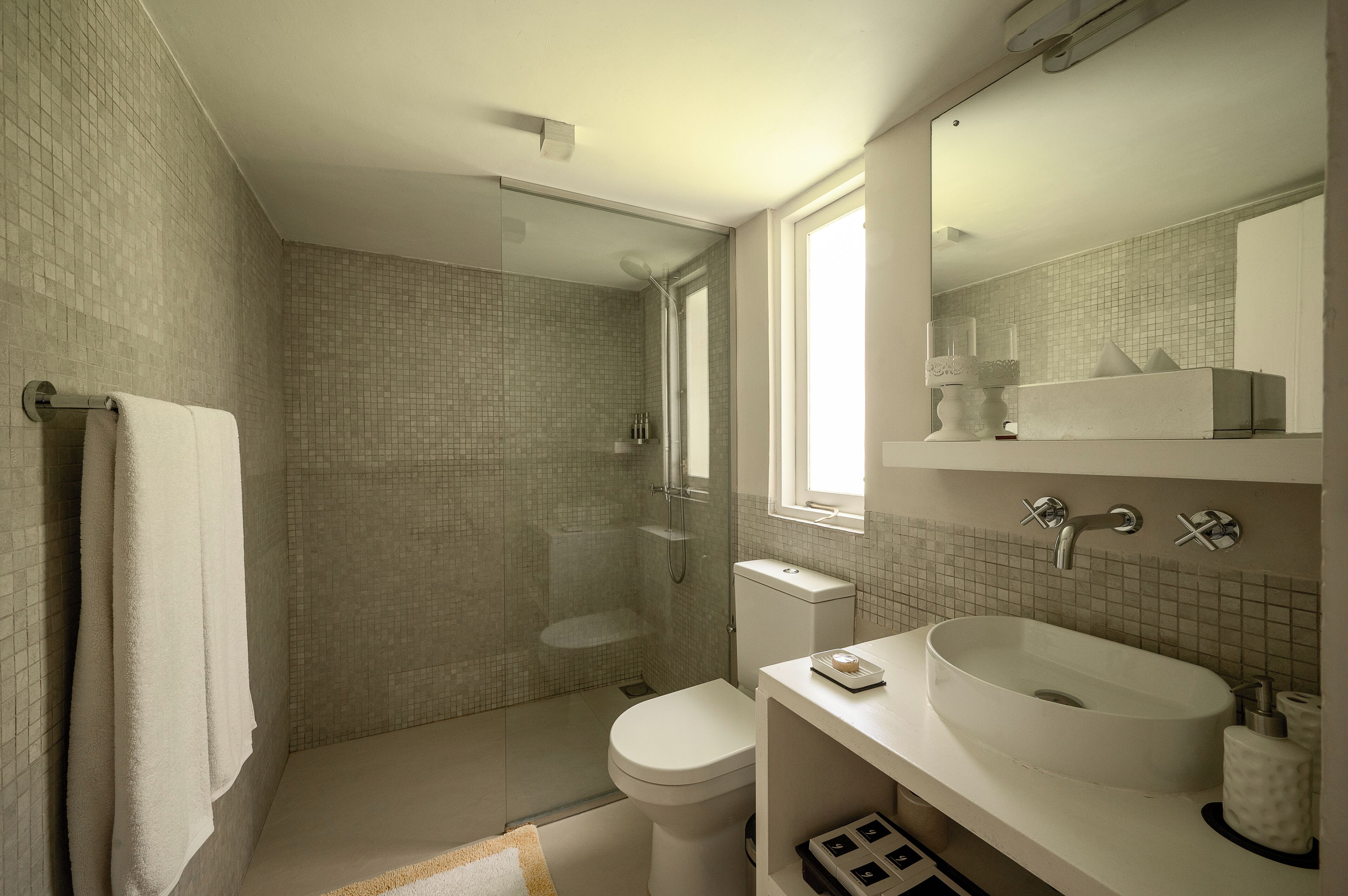 A modern bathroom with a glass-enclosed shower, a white toilet, and a large sink with a mirror above.
