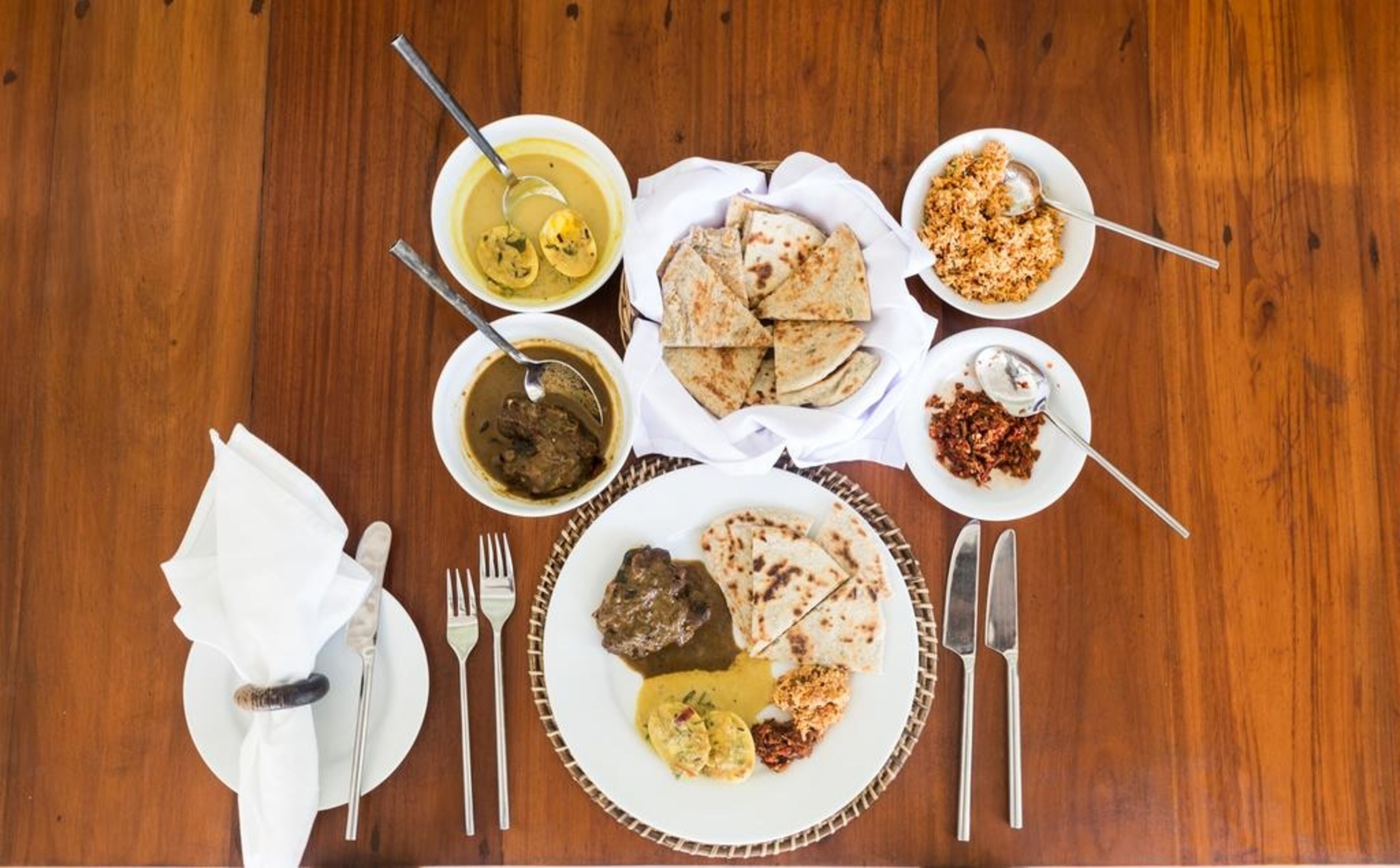 A table set with various dishes, utensils, and a napkin.