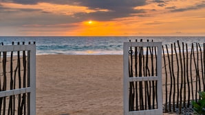 A beach with a wooden fence and a sunset in the background. - 906 Hikkaduwa - Private Beachfront Villa (Hikkaduwa)