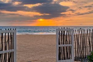 Una playa con una valla de madera y un atardecer al fondo.
