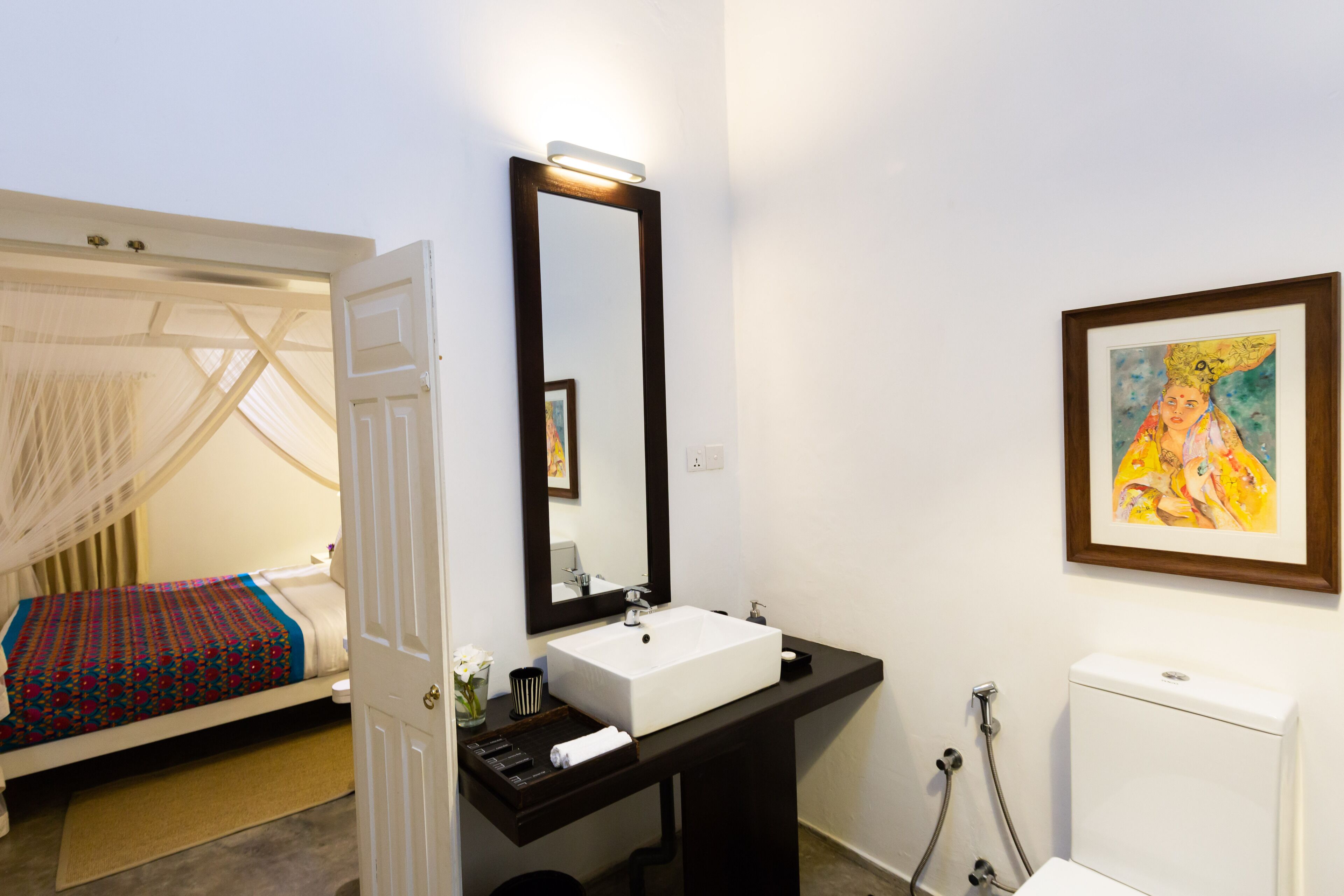 A bedroom with a bed, bedside table, and a large mirror.