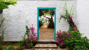 Un bâtiment blanc avec une porte turquoise qui mène à un sentier pavé de pierres.