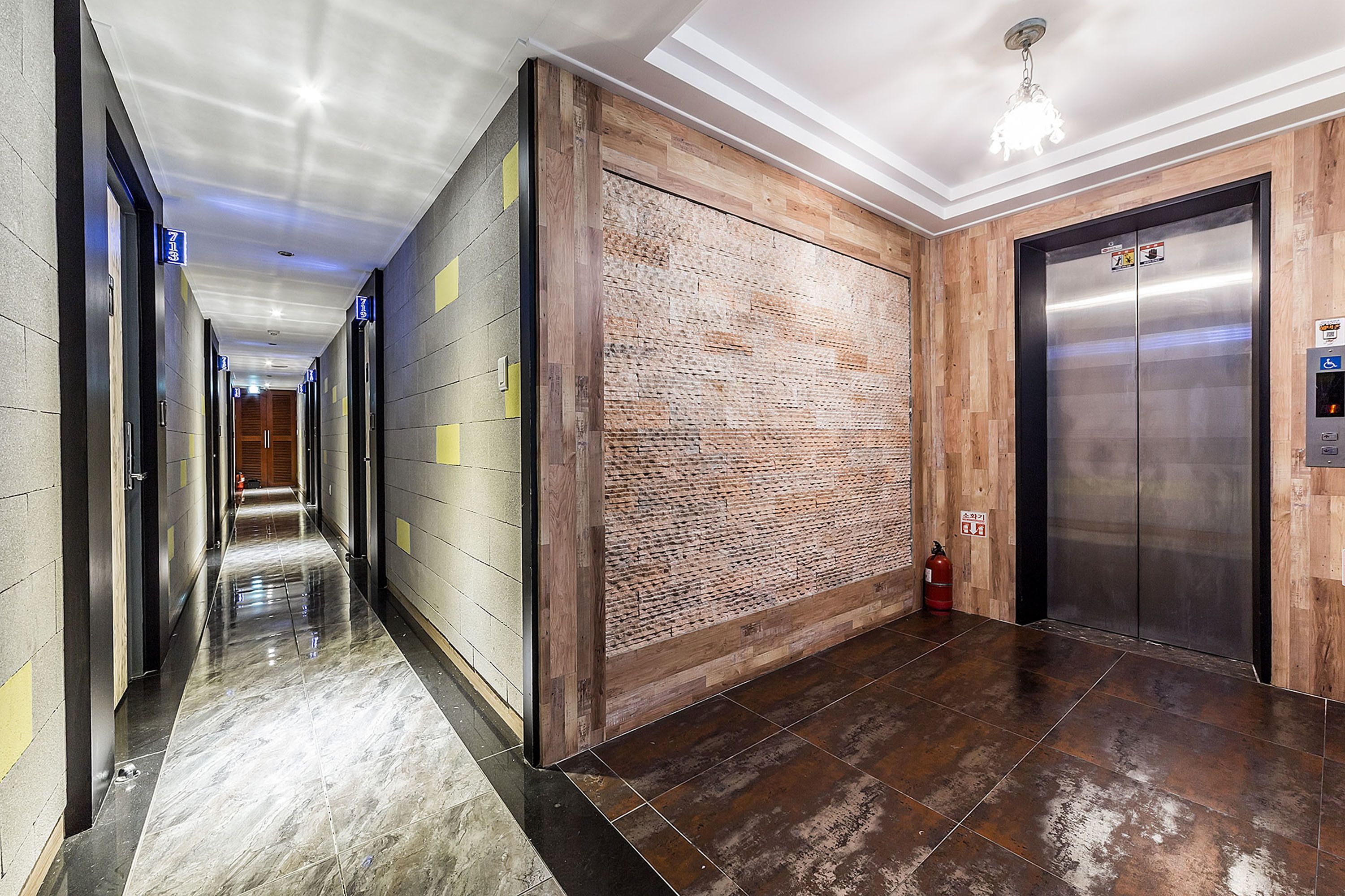 A modern hallway with a polished floor, a wooden accent wall, and an elevator.