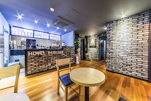 A hotel lobby with a wooden floor, a reception desk, and a brick wall. - Duruwa Hotel (Incheon)