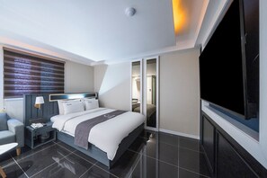 Une chambre d’hôtel moderne équipée d’un grand lit, d’un bureau, d’une chaise, d’une télévision et d’une armoire.