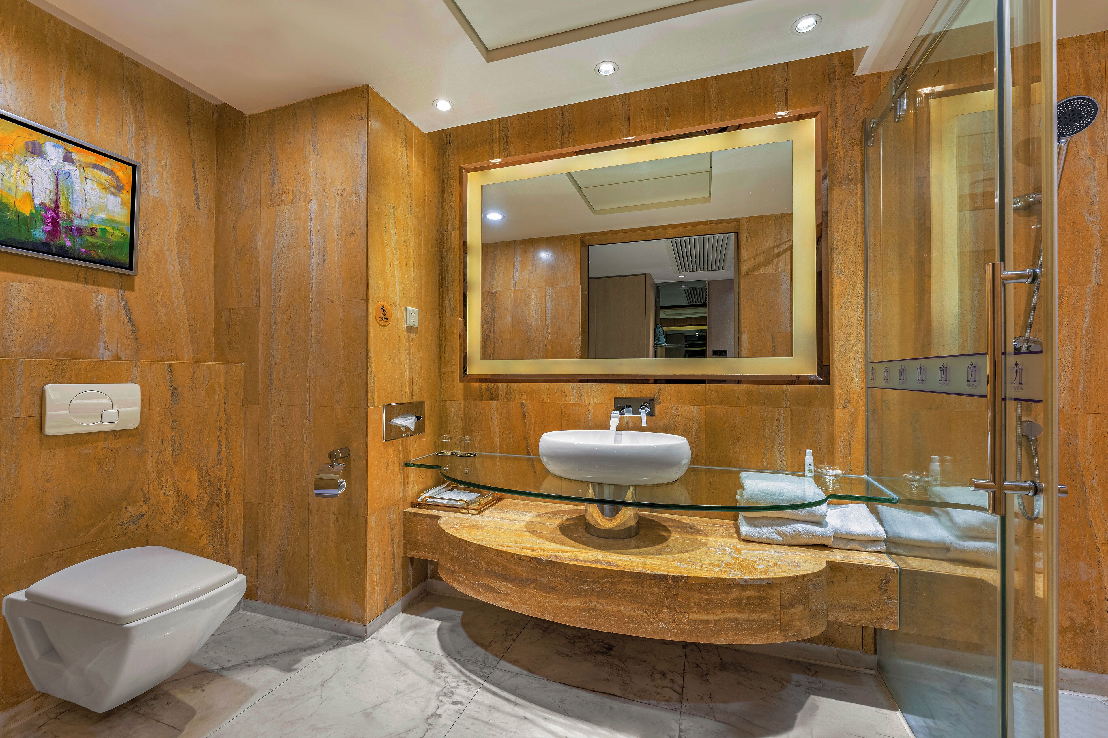 A modern bathroom with a marble vanity, a glass shower enclosure, and a large mirror.