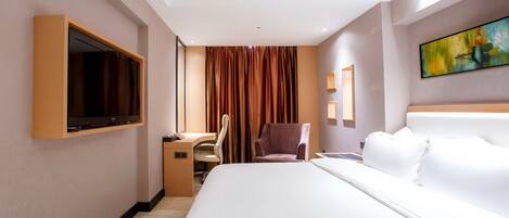 Habitación de hotel con una cama grande, un escritorio con silla, un televisor montado en la pared y un cuadro sobre la cama.