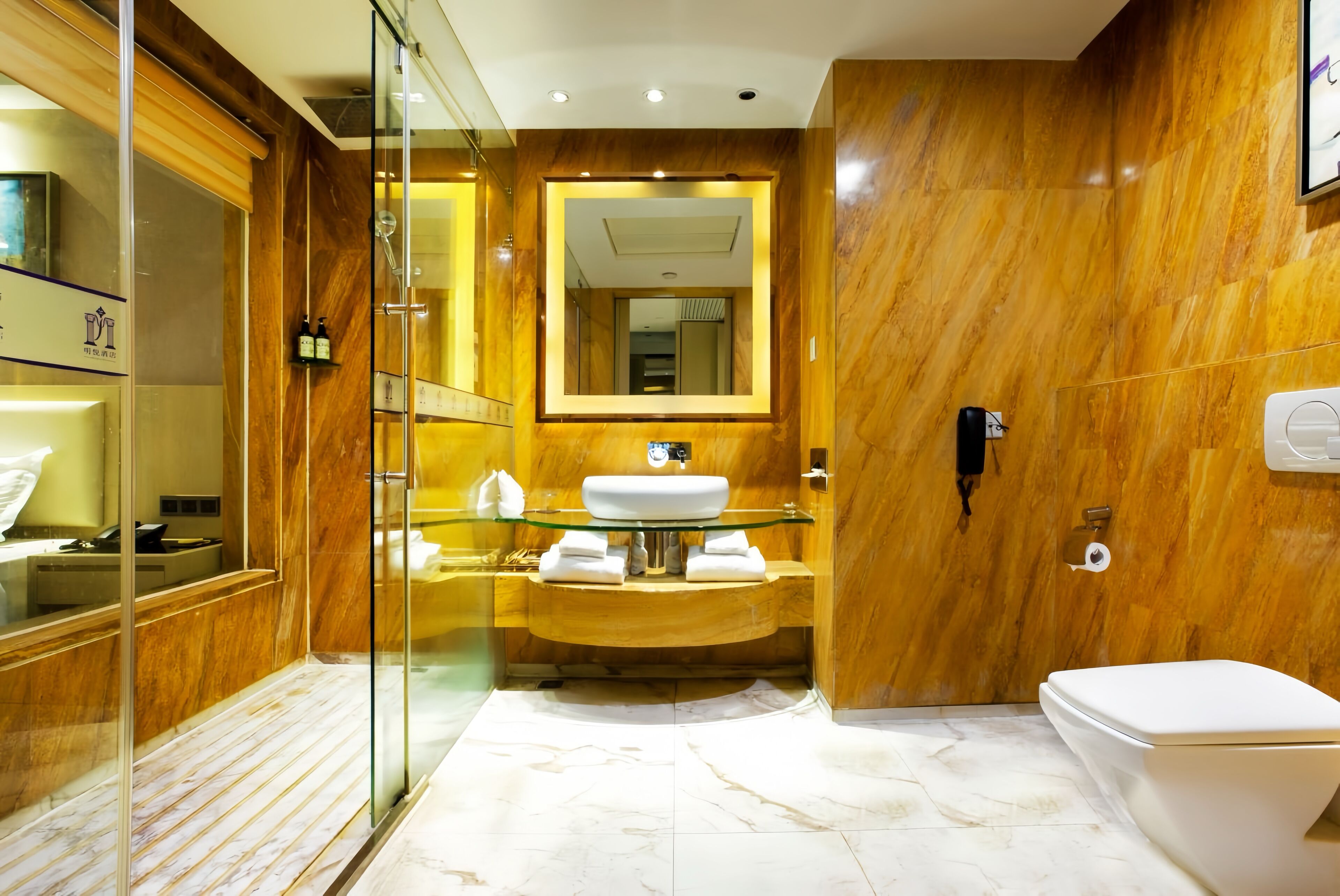 A modern bathroom with a glass-enclosed shower, a marble sink, and a toilet.