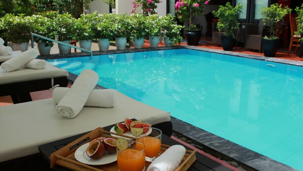 A poolside area with lounge chairs, a tray with fruit and drinks, and potted plants around the pool. - Phuc Thao Villa (Da Nang)