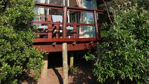 A two-story house with a balcony, surrounded by trees. - Buccaneers Backpackers (Great Kei)