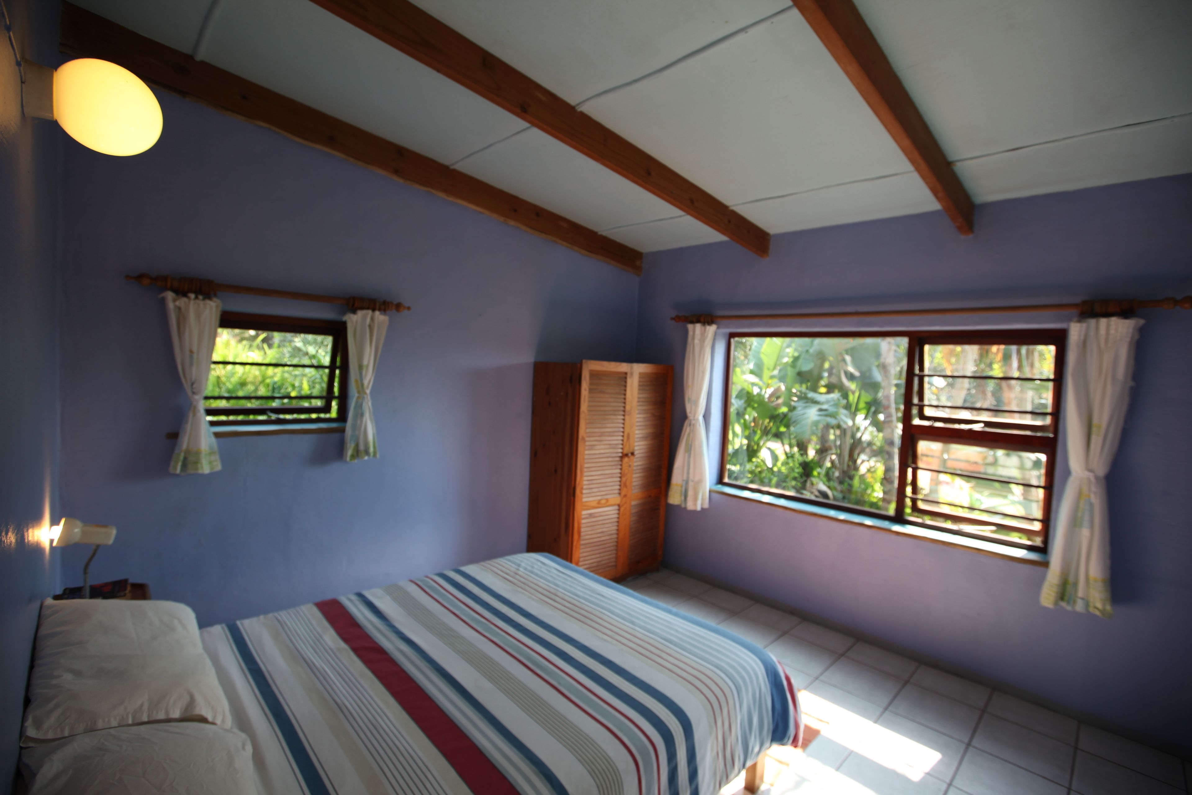 Een slaapkamer met een bed, een kledingkast en een raam met gordijnen.