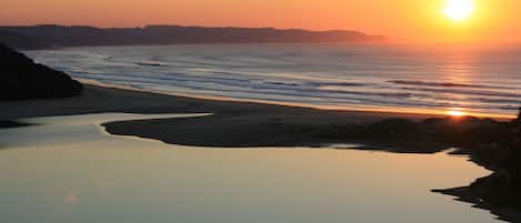 A coastal sunset view with calm waters reflecting the sky.