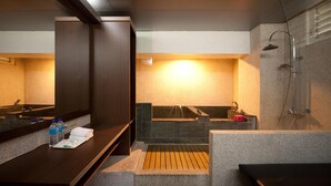 Un baño moderno con un espejo grande, una bañera, una ducha y un tocador con una toalla y botellas de agua.