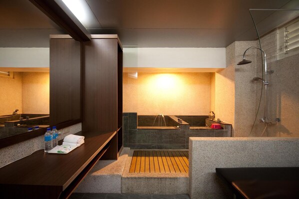 A modern bathroom with a large mirror, a bathtub, a shower, and a vanity with a towel and water bottles. - Champagne Hotel (Jiaoxi)