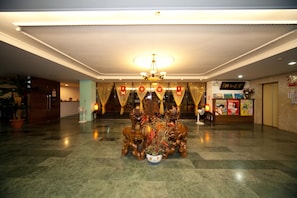 A lobby with a chandelier, a reception desk, and a decorative wooden sculpture with plants. - Champagne Hotel (Jiaoxi)