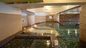 Un área de spa con una bañera de hidromasaje, suelo de baldosas y una escalera.