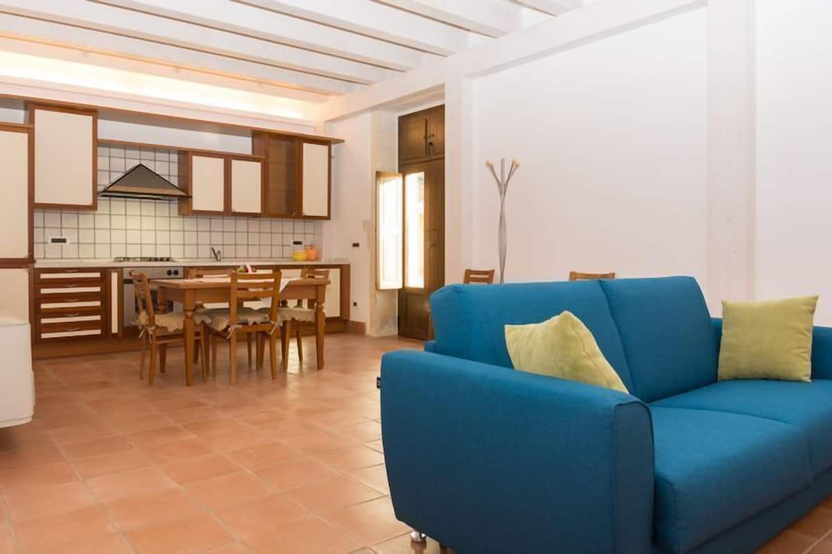 Ein modernes Wohnzimmer mit einem blauen Sofa und einem Essbereich mit Holzmöbeln.