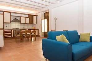 Uma sala de estar moderna com um sofá azul e uma área de jantar com mobiliário de madeira.