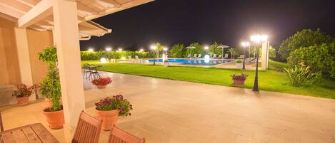 An outdoor patio area with a pool, chairs, and potted plants.