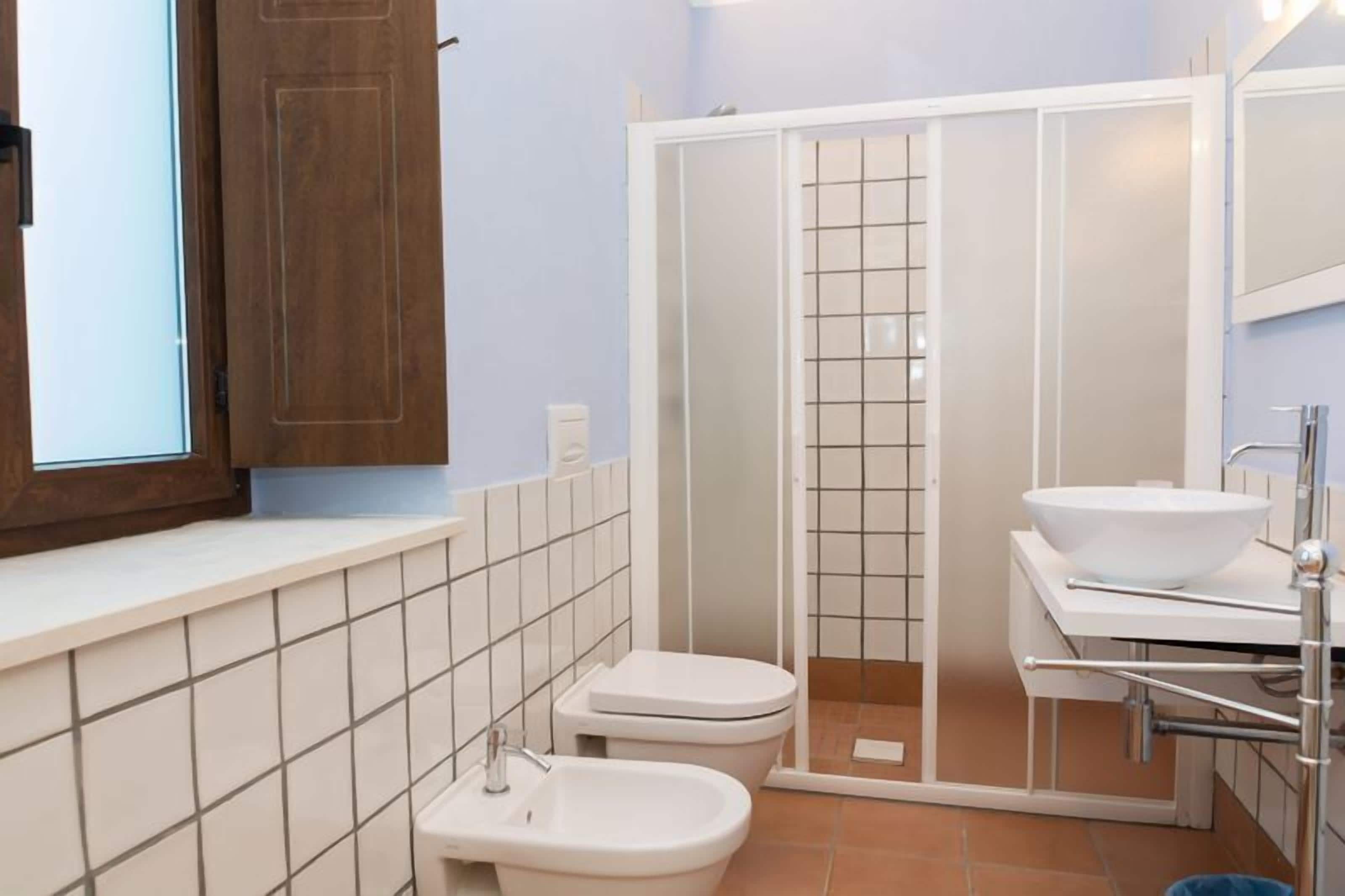 Un bagno con WC, bidet e doccia a pavimento con porta in vetro.