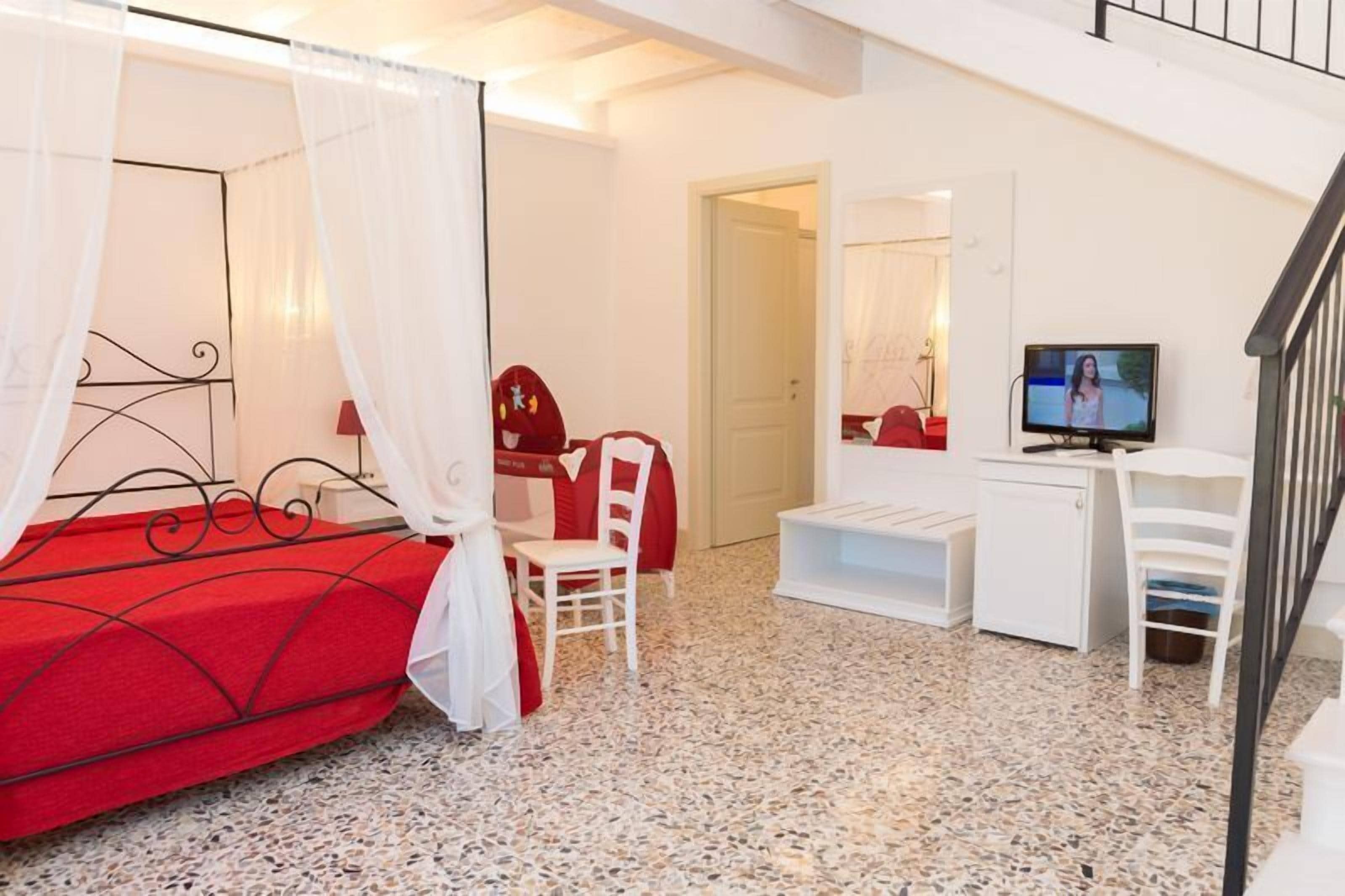 A bedroom with a bed, a desk, a chair, and a television.