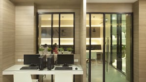Um espaço de escritório moderno com divisórias de vidro, várias estações de trabalho com computadores e uma área de receção.
