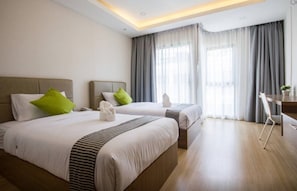 Habitación de hotel con dos camas, un escritorio y una silla.
