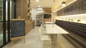 Um café moderno com cardápio na lousa, mesas brancas e um banco estofado escuro.