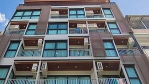 Um edifício com várias andares, varandas e aparelhos de ar condicionado.