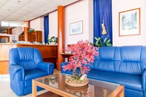 A reception area with a desk, chairs, and a decorative plant. - Hotel Omorika (Punat)