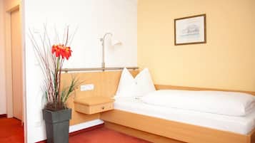 Habitació compacte amb un llit individual, una taula de nit, una làmpada i un quadre al mur.