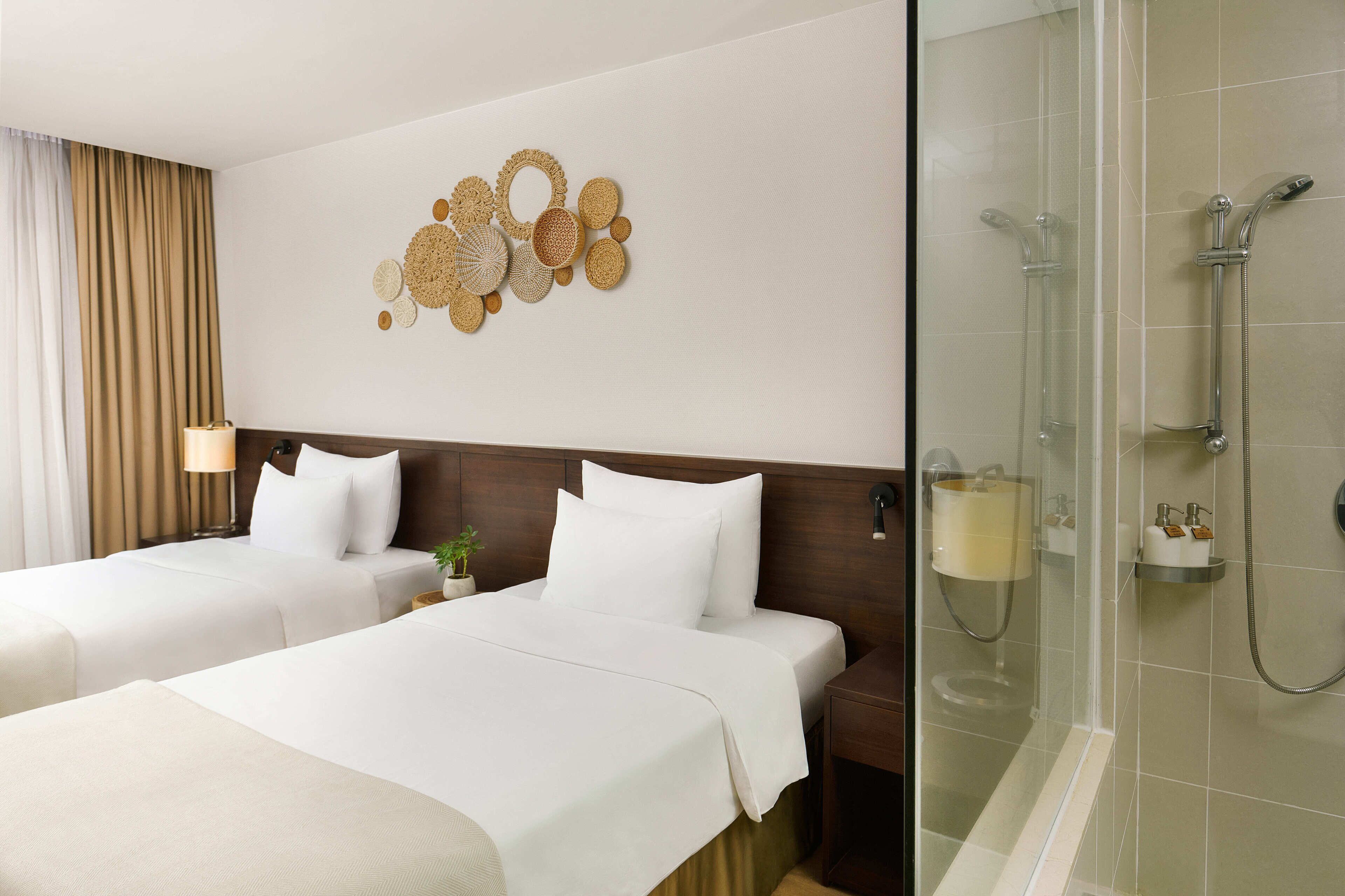 A hotel room with two beds, a shower, and a wall art piece.
