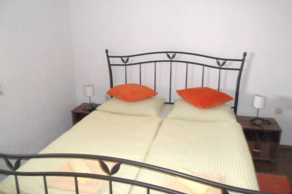 A bed with a metal frame, two pillows, and a bedside table with a lamp.