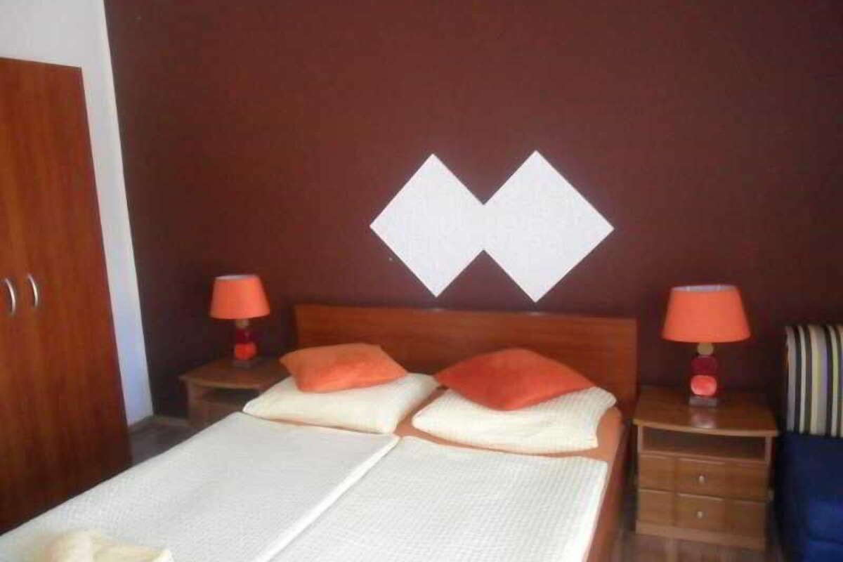 A hotel room with a bed, two nightstands, a wooden wardrobe, and a wall with a geometric design.