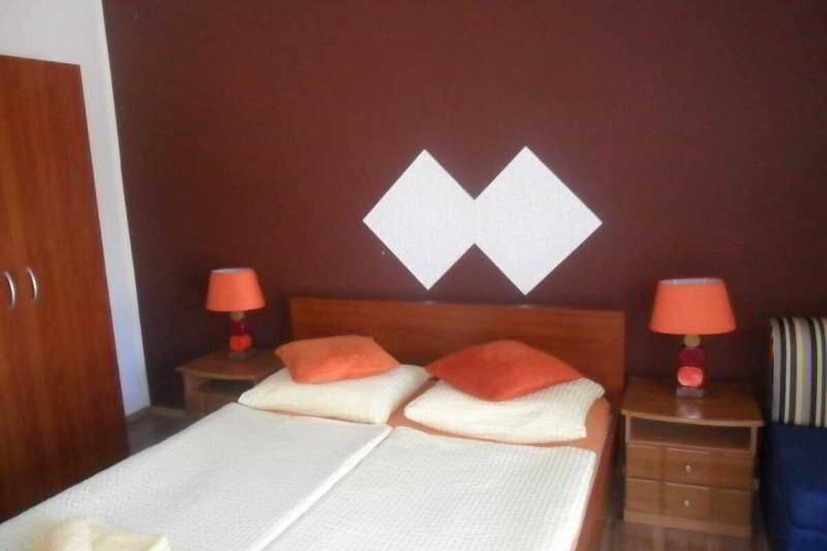 A hotel room with a bed, two nightstands, a wooden wardrobe, and a wall with a geometric design.
