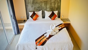 A neatly made bed with white linens, two decorative pillows, and a towel arranged in a swan shape on the bed. - Budchui Village 2 (Koh Tao)